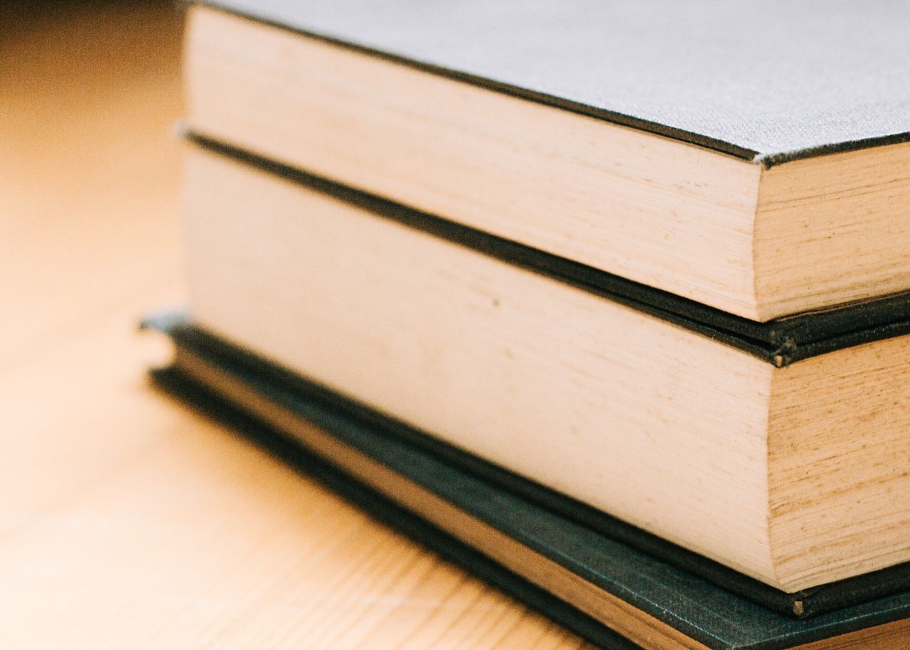 Close-up image of a stack of hardcover books, emphasizing knowledge and literature.